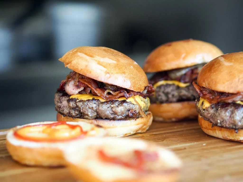 Gourmet cheeseburger with bacon, melted cheddar, caramelized onions on wood.