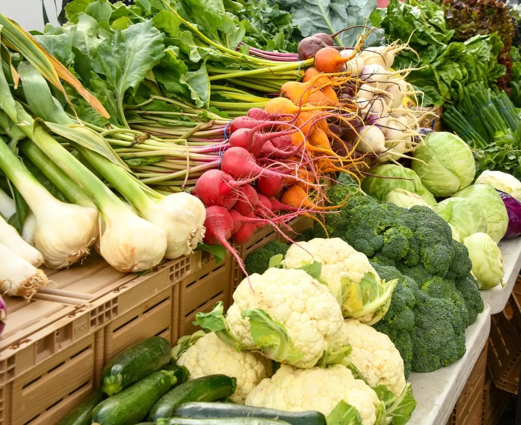 Bountiful market display of fresh, colorful root vegetables and leafy greens.