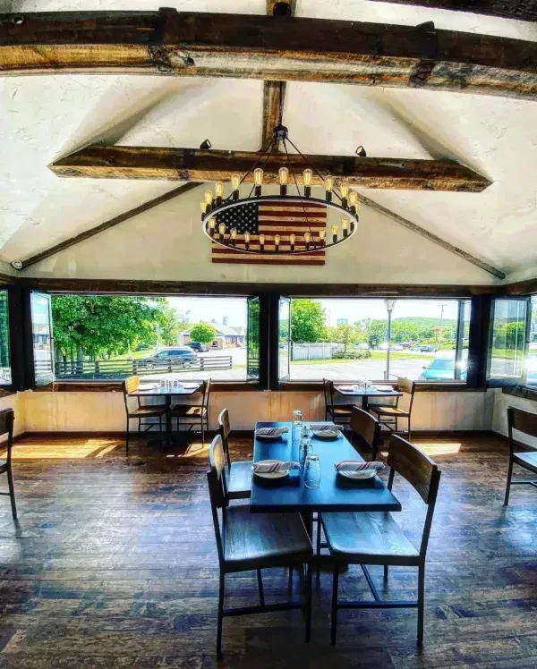 Empty restaurant dining room with vaulted ceiling and American flag chandelier.