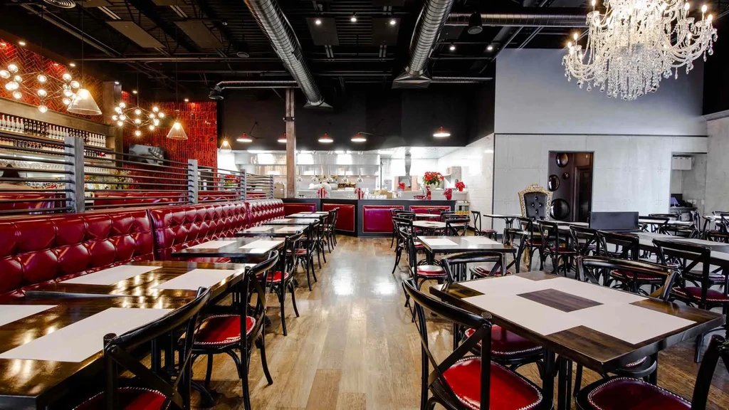 Spacious restaurant interior with red booths, dark tables, and industrial-chic decor.