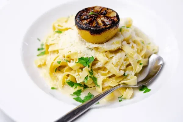 Creamy pasta with Parmesan, parsley, and a charred lemon half.