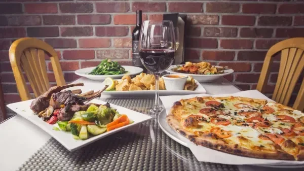 Various dishes and red wine on a restaurant dining table.