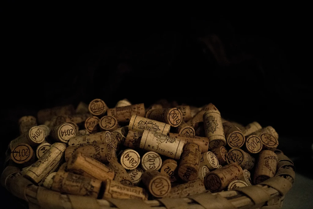 Rustic basket overflowing with used wine corks, some marked 2013/2014.