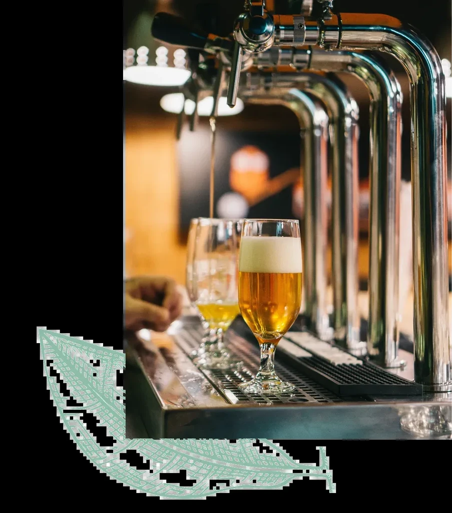 Polished chrome beer taps pouring golden beer into a partially full glass.