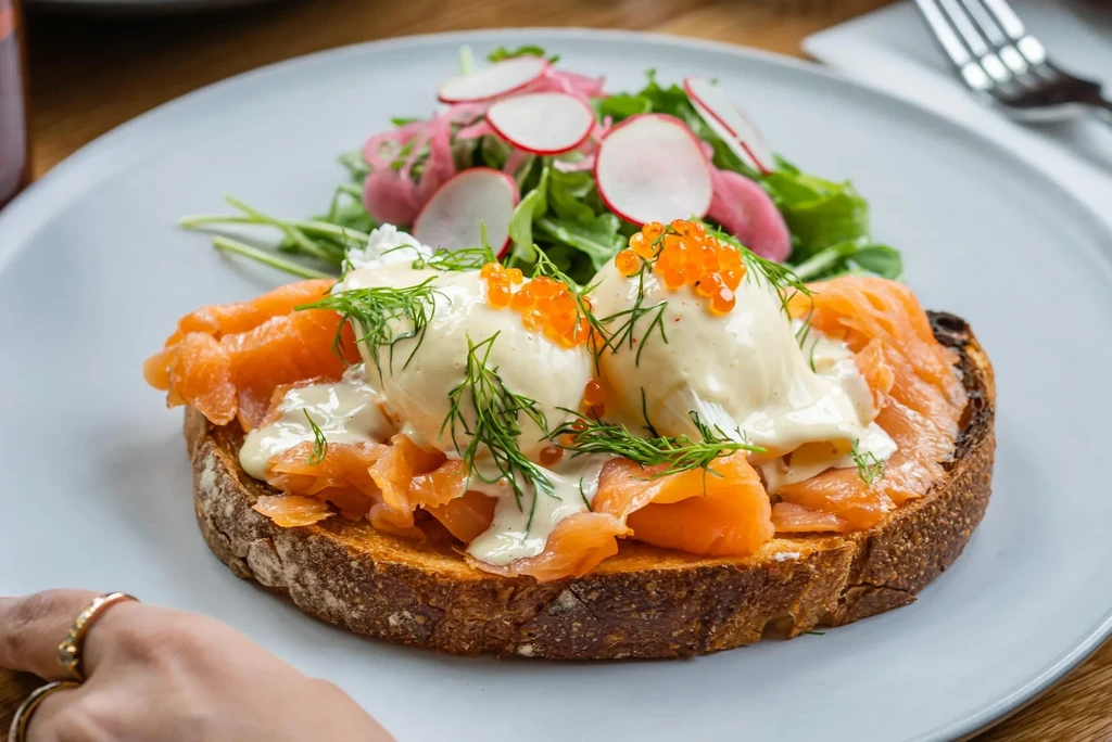 Salmon toast with poached eggs, hollandaise, dill, and a radish salad.