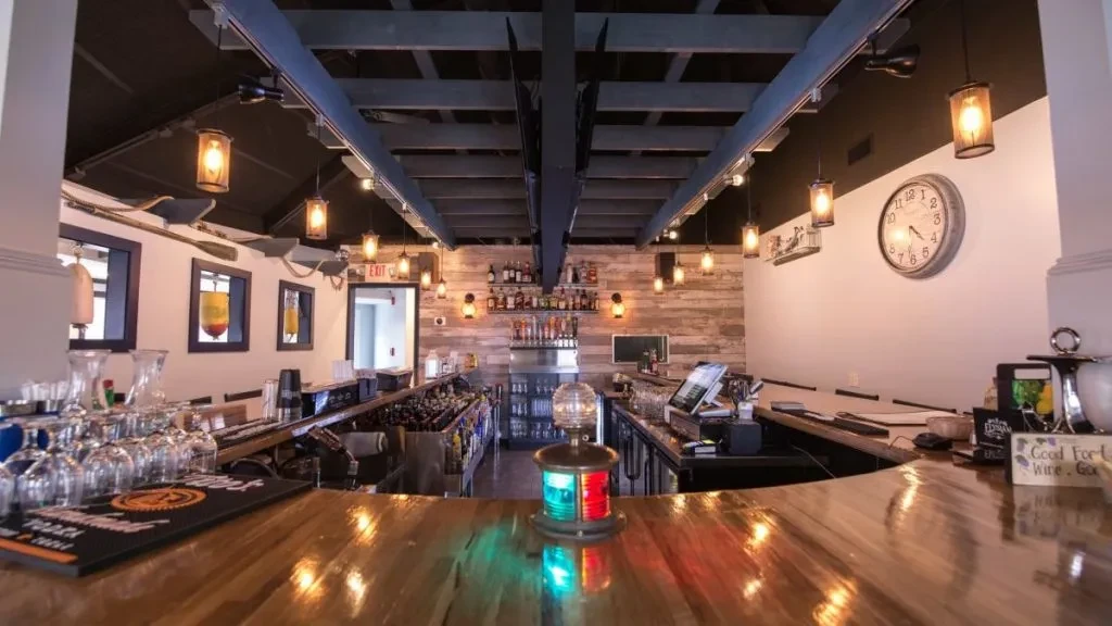 An empty bar with a wooden counter and nautical-themed decor.