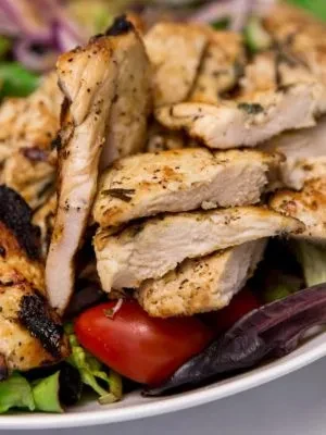 Close-up of grilled chicken pieces with charred edges on a plate.