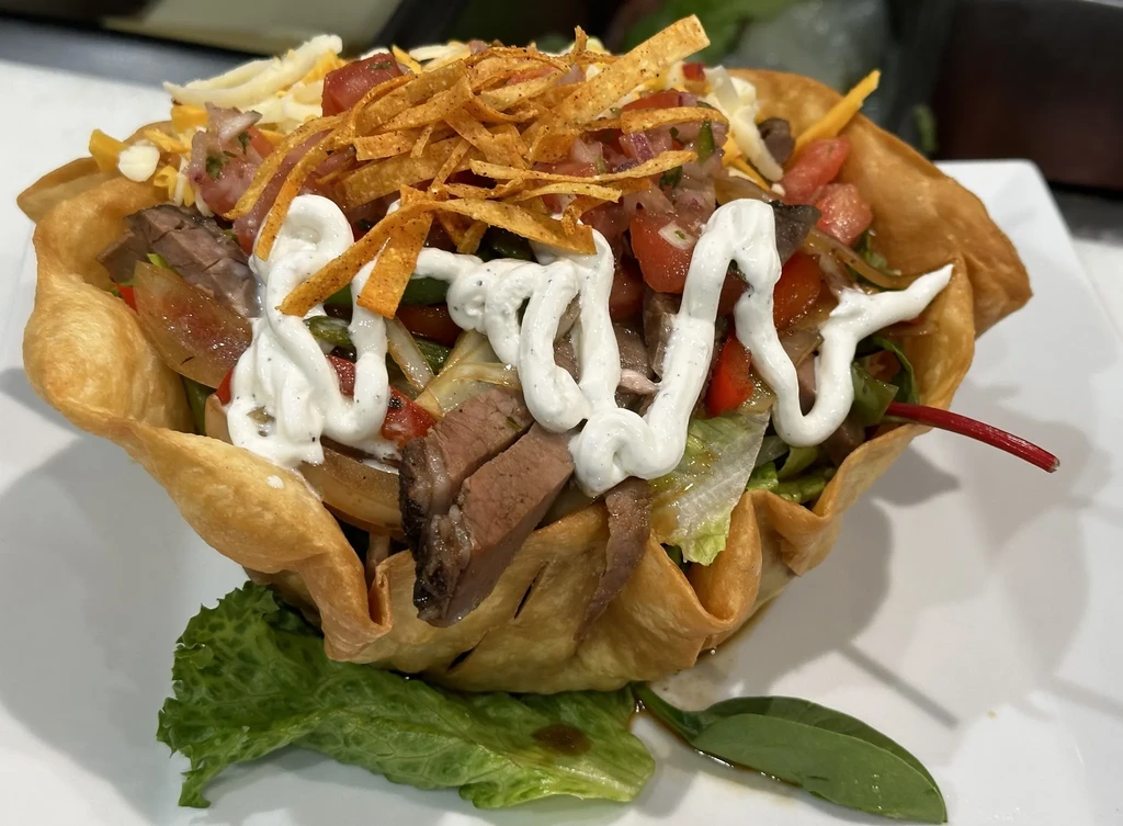 Vibrant taco salad in a crispy tortilla bowl with meat, lettuce, and salsa.