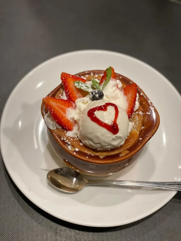 Dessert topped with ice cream, berries, mint, whipped cream, heart sauce.
