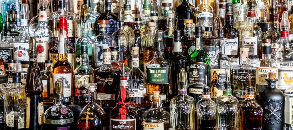 A well-lit bar shelf filled with various spirit and liqueur bottles.
