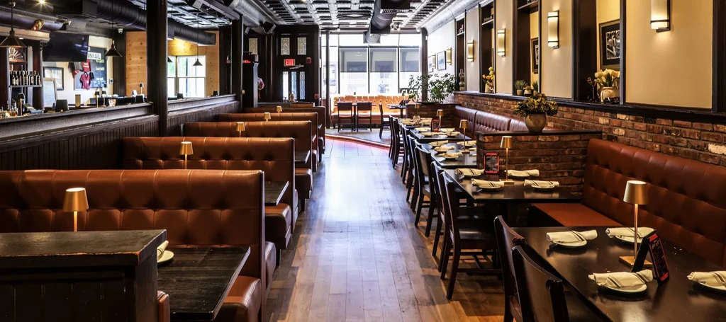 Empty, stylish restaurant interior with booths, dining tables, and a bar.