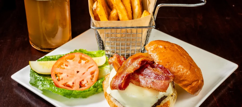 Open-faced bacon cheeseburger, lettuce, tomato, pickle, fries, and beer.