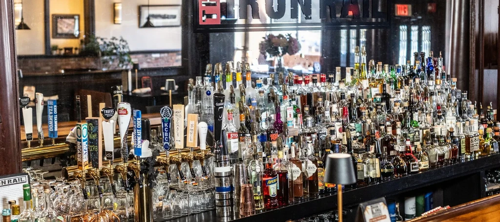Well-stocked bar counter with liquor bottles, beer taps, and glassware.