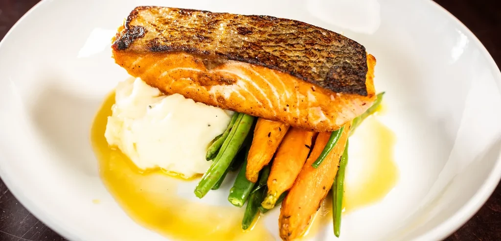 Crispy salmon on mashed potatoes with string beans and glazed carrots.