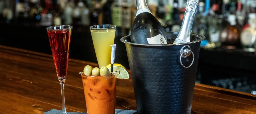 Cocktails and sparkling wine in a bucket on a wooden bar.
