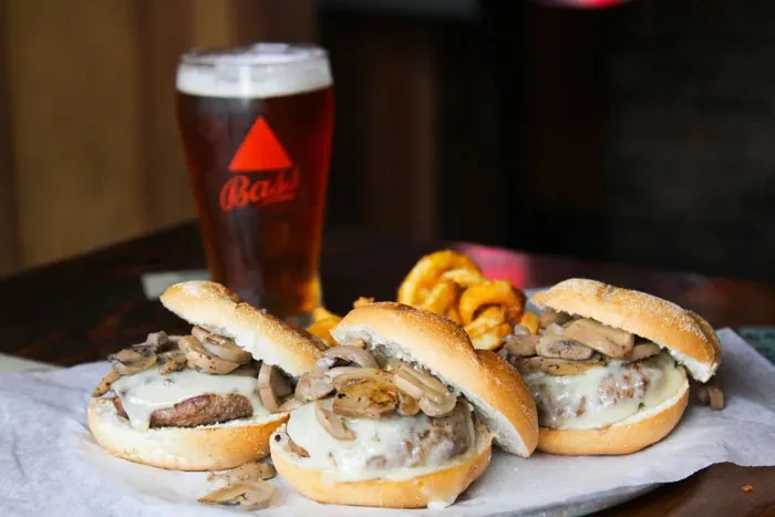 Sliders with cheese, mushrooms, curly fries, and a Bass beer.
