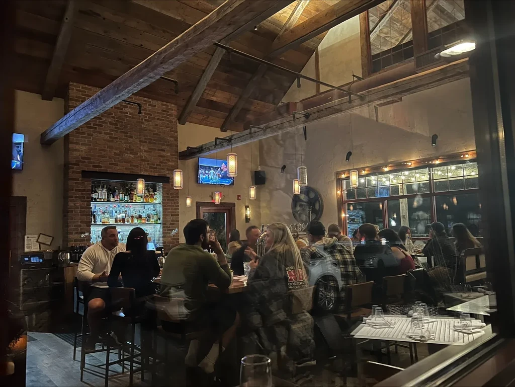 Bustling, rustic bar and restaurant with exposed wood beams and patrons.