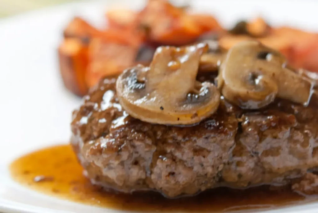 Thick meat patty with sautéed mushrooms and brown sauce.