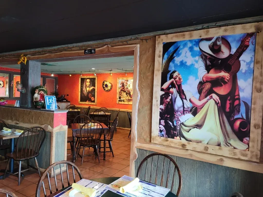 Mexican restaurant dining room with orange walls, art, and decor.