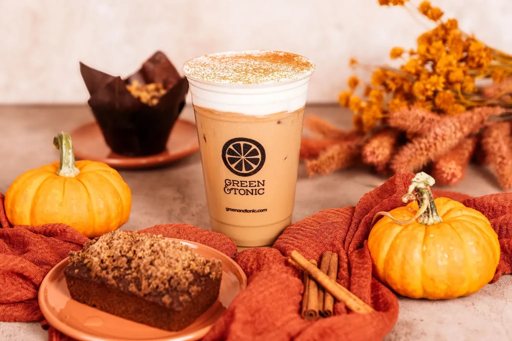 Iced coffee with baked goods, pumpkins, cinnamon, and fall decorations.