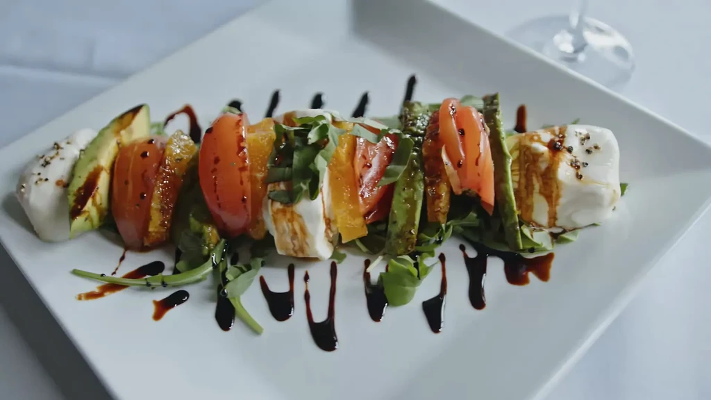 Caprese salad with avocado, tomatoes, mozzarella, arugula, and balsamic glaze.