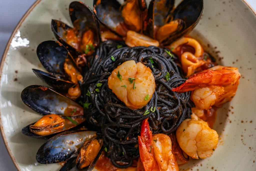 Black squid ink pasta with mussels, shrimp, and scallops in tomato sauce.