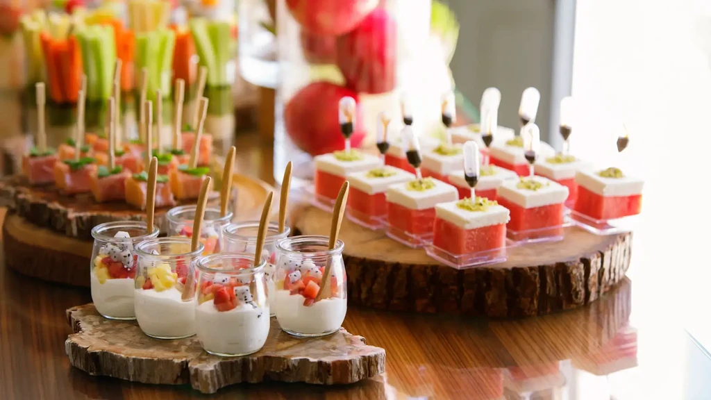 A table displaying various appetizers, including fruit parfaits, pastries, and savory skewers.