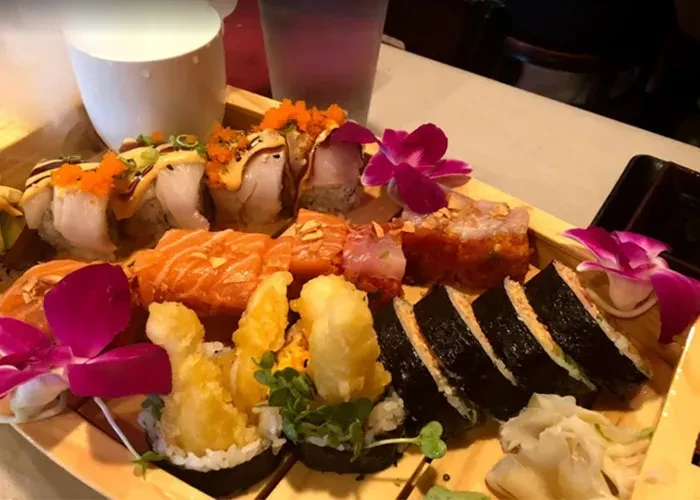 Sushi and sashimi boat with maki, salmon, tempura, and orchids.