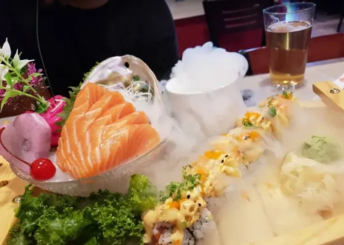 Salmon sashimi and sushi platter dramatically presented with smoke.