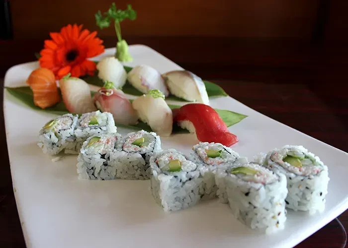 Platter of sushi and sashimi with nigiri, maki, and floral garnish.