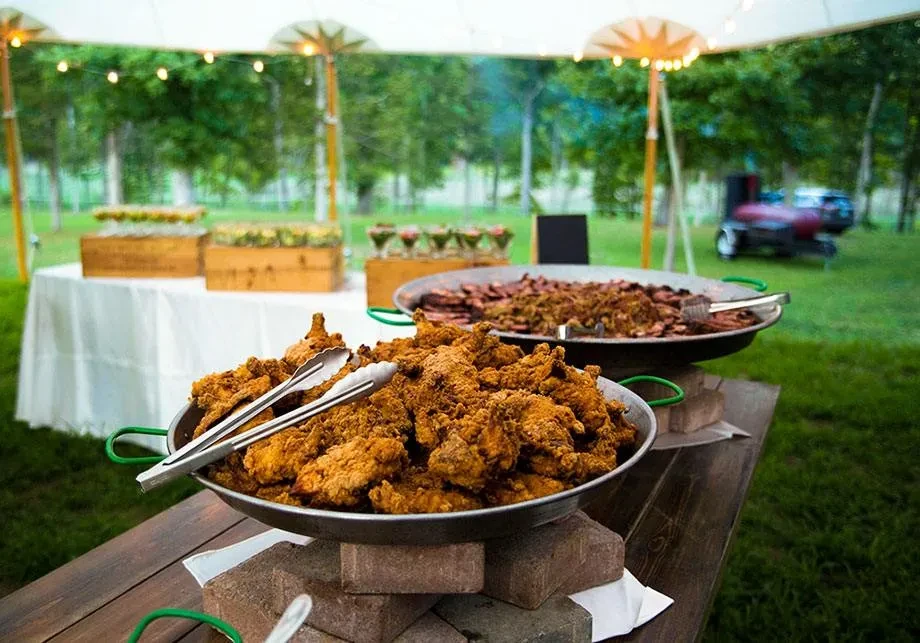 Outdoor catering with fried chicken and another savory dish in pans.