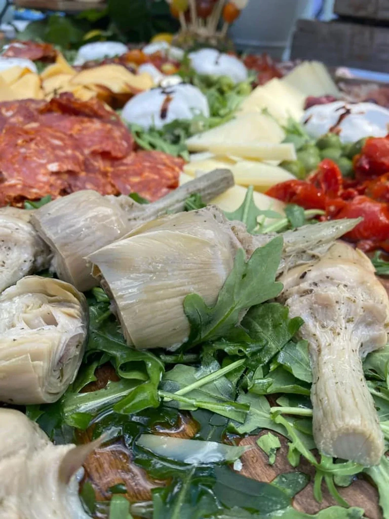 Close-up antipasto platter with artichokes, salami, cheeses, and sun-dried tomatoes.