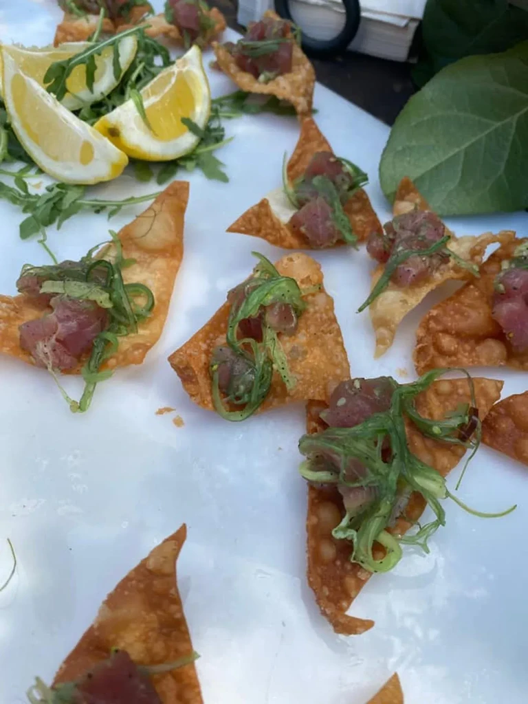 Overhead view of tuna poke on wonton chips with seaweed and lemon.