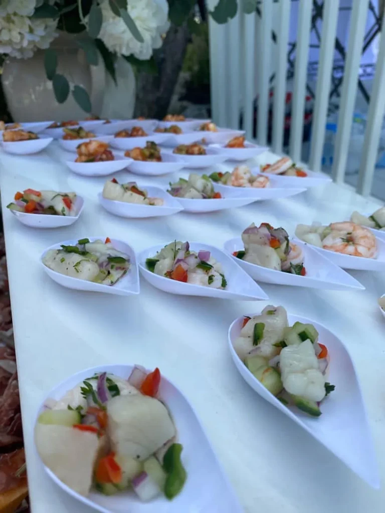 White tear-drop spoons hold seafood ceviche and shrimp appetizers outdoors.