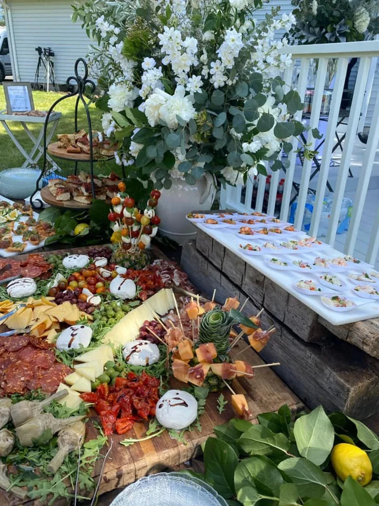 Vibrant outdoor buffet with charcuterie, appetizers, and a floral centerpiece.