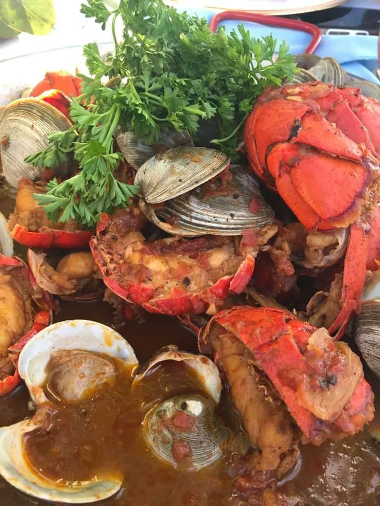Lobster and clams in a rich, reddish sauce, garnished with fresh parsley.