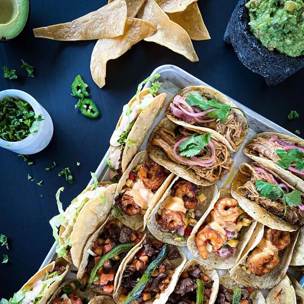 Overhead shot of a tray of tacos, chips, and guacamole.