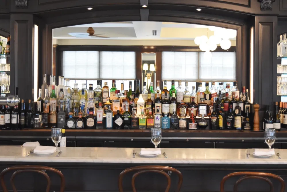 A full bar with many bottles of liquor and wine, set for dining.