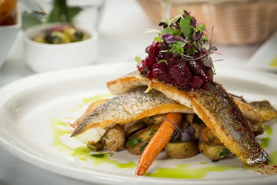 Pan-seared fish fillets with roasted vegetables, beetroot relish, and microgreens.