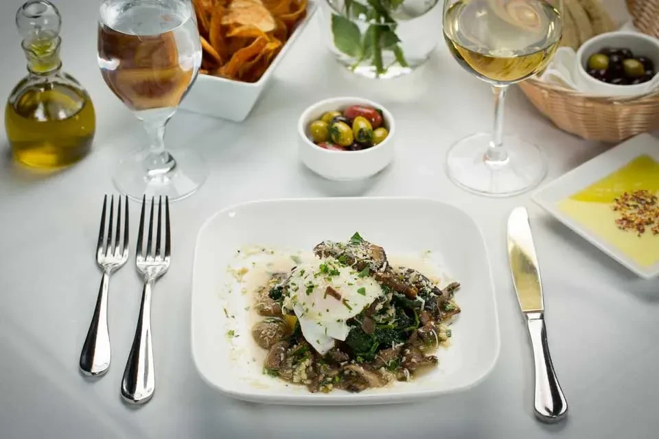 Plated meal with poached egg, mushrooms, spinach, olives, and wine.