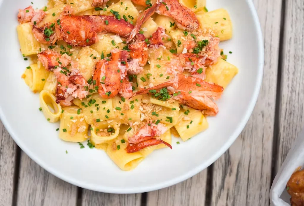 Lobster pasta dish topped with chives on a white plate.