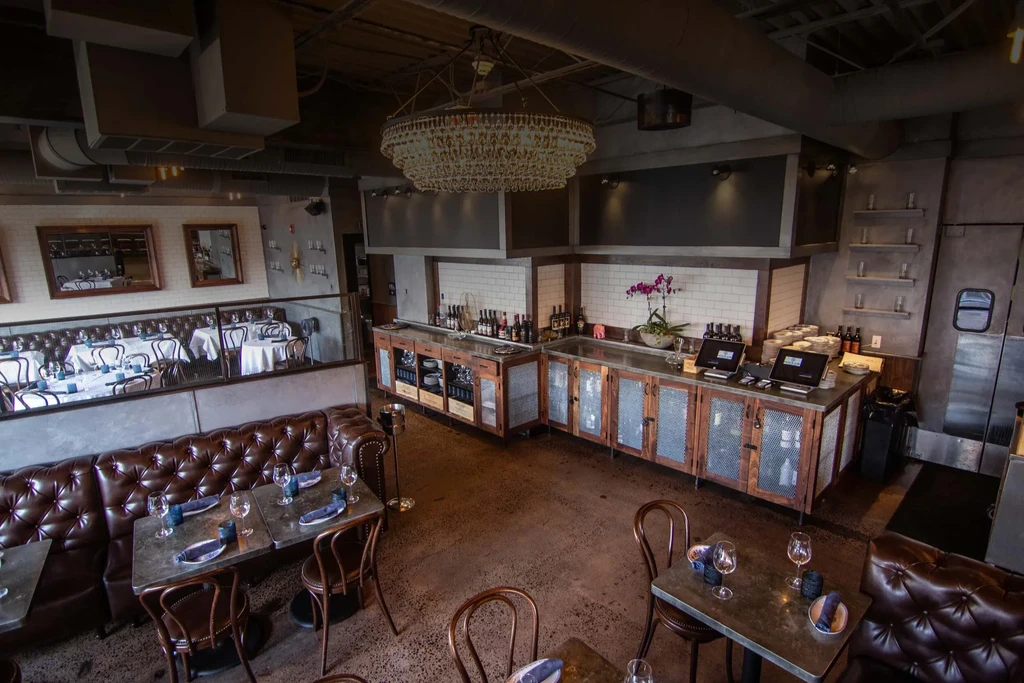 Upscale restaurant with brown leather booths, bar area, and chandelier.