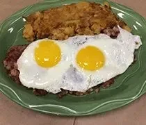 Two fried eggs, ground meat, and hash browns on a green plate.
