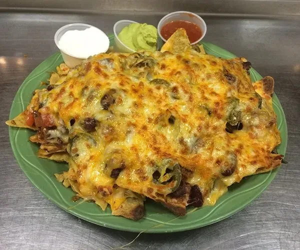 A plate of loaded nachos with melted cheese, jalapeños, and dips.