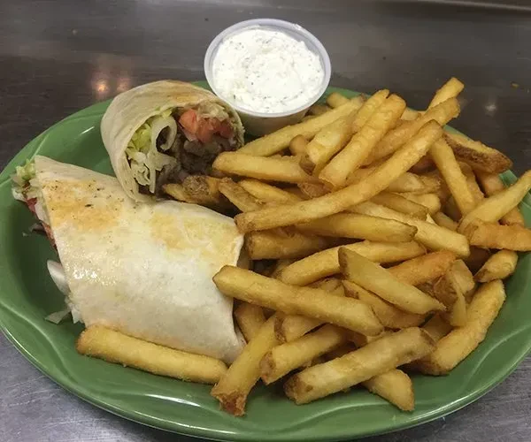 Gyro wrap with fries and dipping sauce on a green plate.