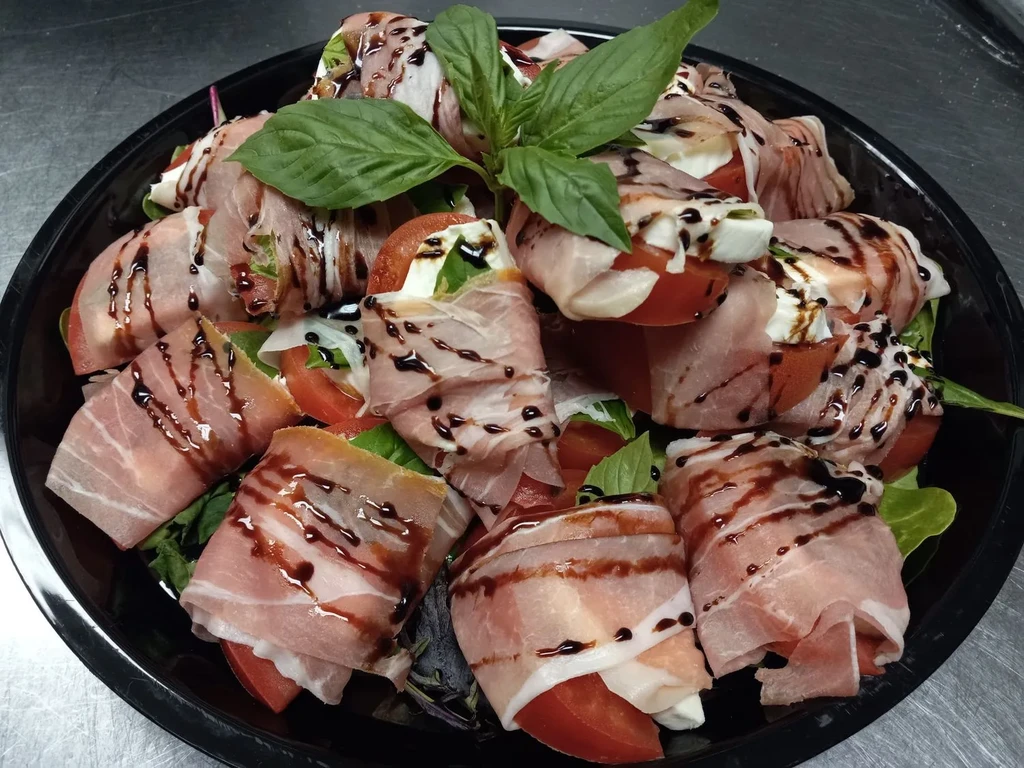 Prosciutto-wrapped tomatoes and mozzarella with balsamic glaze and basil.