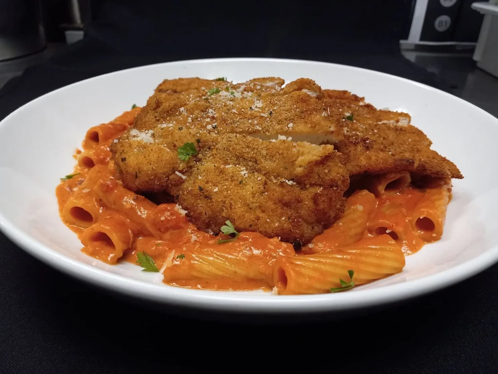 Crispy chicken cutlets on rigatoni pasta with a pink sauce.