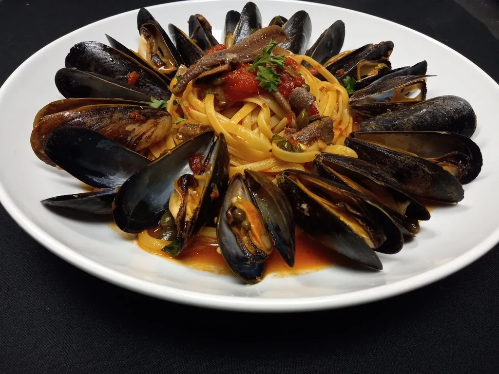 Linguine with mussels in a tomato sauce, garnished with anchovies.