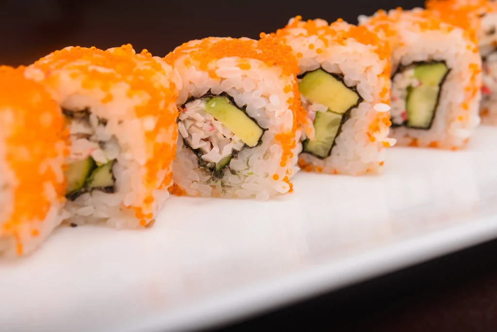 A row of California sushi rolls topped with tobiko.