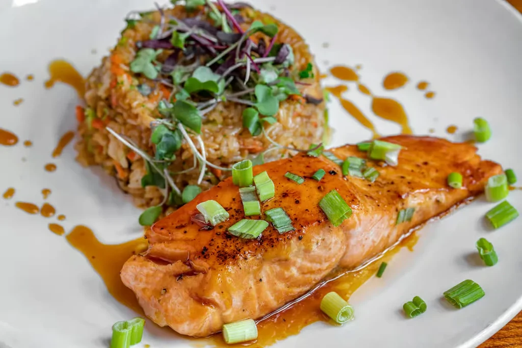 Cooked salmon fillet with scallions and a side of rice.